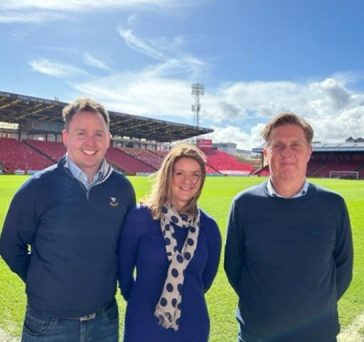 This image depicts three Aberdeen FC charitable trust ambassadors, including newly appointed Iain Landsman, Director of Hutcheon Mearns Real Estate, to the left.